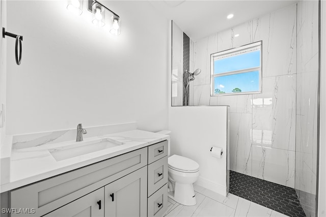 bathroom featuring a tile shower, vanity, and toilet