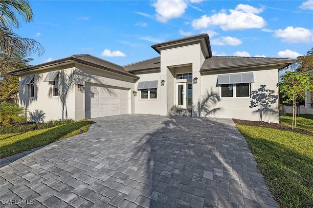 prairie-style house featuring a garage, decorative driveway, and stucco siding