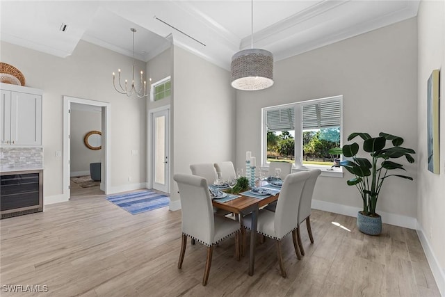 dining space featuring light wood-style floors, baseboards, a chandelier, and crown molding