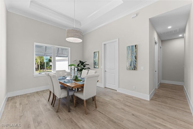 dining room with a tray ceiling, light wood finished floors, recessed lighting, visible vents, and baseboards