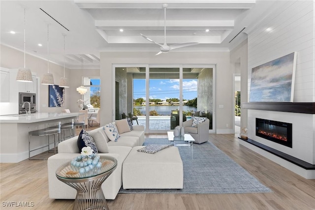 living area with light wood finished floors, recessed lighting, a glass covered fireplace, beamed ceiling, and baseboards