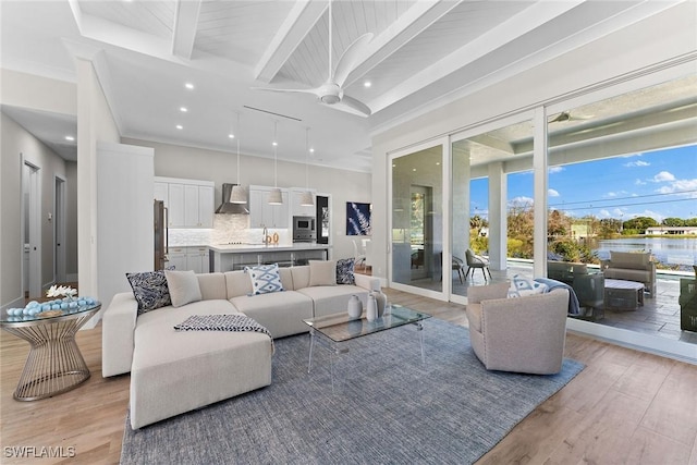 living room with light wood finished floors, ornamental molding, a ceiling fan, and beamed ceiling