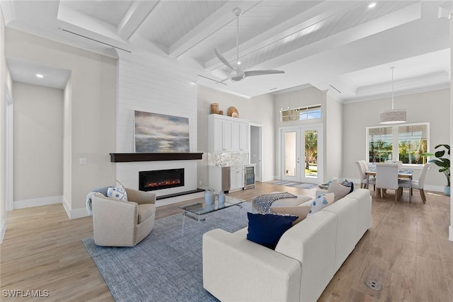 living area with light wood finished floors, a fireplace, baseboards, and french doors