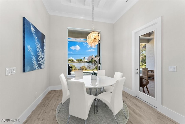 dining area featuring crown molding, light wood-style flooring, and baseboards