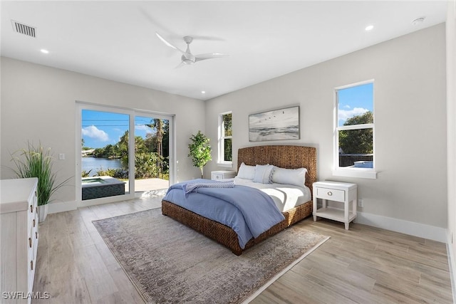 bedroom with access to exterior, a water view, visible vents, and light wood finished floors