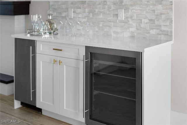 bar featuring a bar, light wood-style floors, beverage cooler, and decorative backsplash