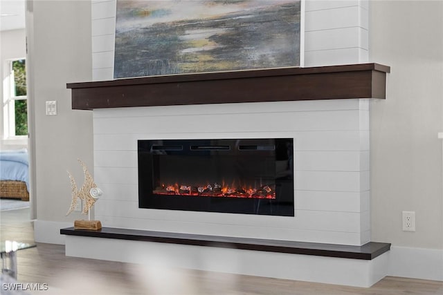 interior details with wood finished floors and a glass covered fireplace