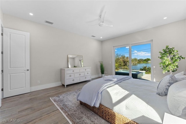 bedroom featuring baseboards, a water view, access to exterior, light wood-style floors, and recessed lighting