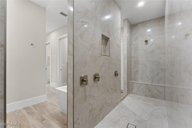 full bath featuring baseboards, visible vents, a marble finish shower, and wood finished floors