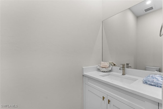 half bathroom with visible vents, vanity, and toilet