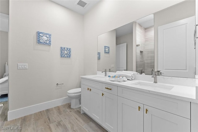 bathroom with wood finished floors, a sink, visible vents, and baseboards