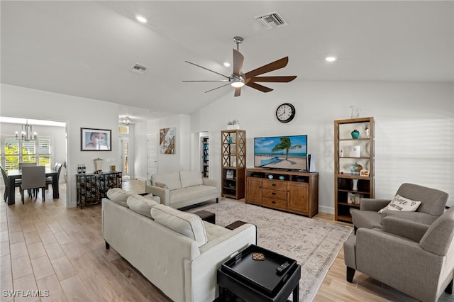 living room featuring ceiling fan with notable chandelier, light wood-type flooring, and vaulted ceiling