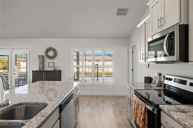 kitchen featuring white cabinetry, sink, light hardwood / wood-style floors, vaulted ceiling, and appliances with stainless steel finishes