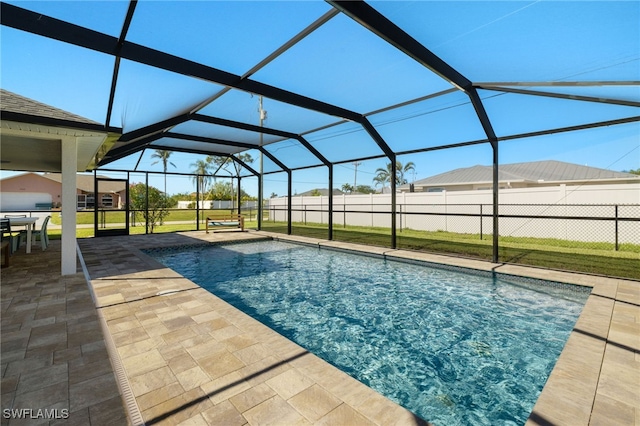 view of swimming pool with glass enclosure, a patio area, and a lawn