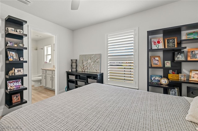 bedroom featuring ceiling fan, light hardwood / wood-style floors, and ensuite bath