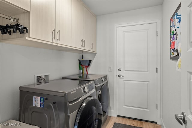 laundry room featuring cabinets, washer and dryer, and light hardwood / wood-style floors