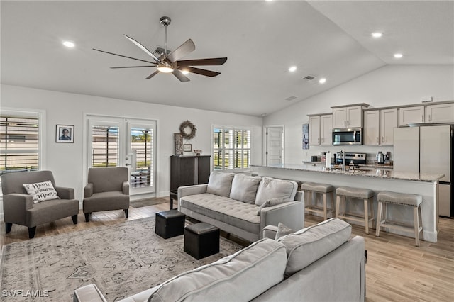 living room with ceiling fan, light hardwood / wood-style floors, lofted ceiling, and sink