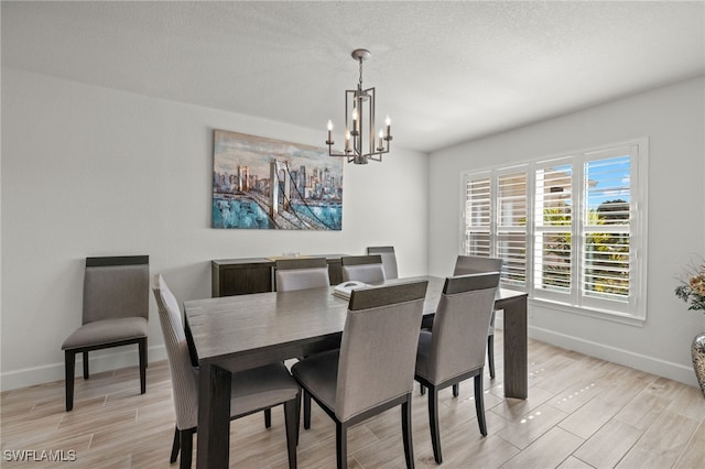 dining area with a notable chandelier, light wood-type flooring, and a textured ceiling