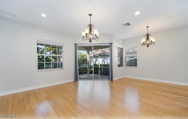 empty room with light hardwood / wood-style floors and an inviting chandelier