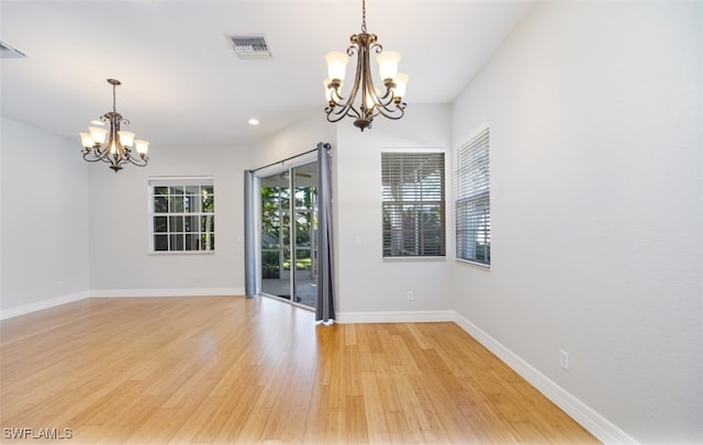 spare room featuring a chandelier and light wood-type flooring