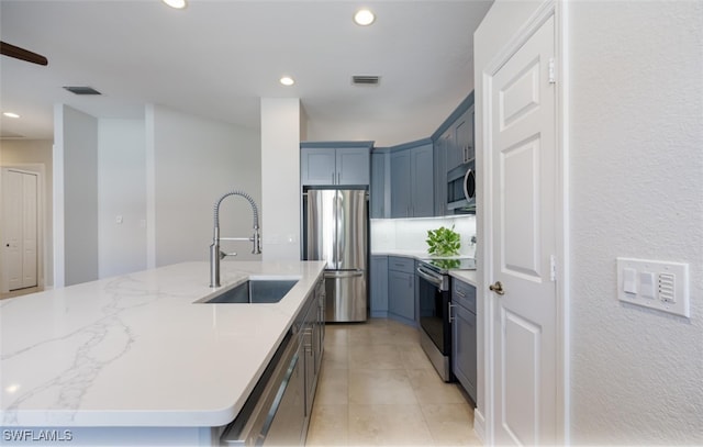 kitchen with sink, light tile patterned floors, stainless steel appliances, and a kitchen island with sink