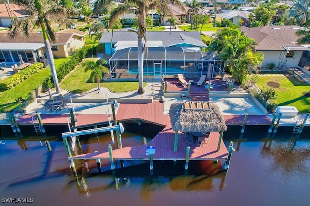 view of dock with a lawn, glass enclosure, and a water view