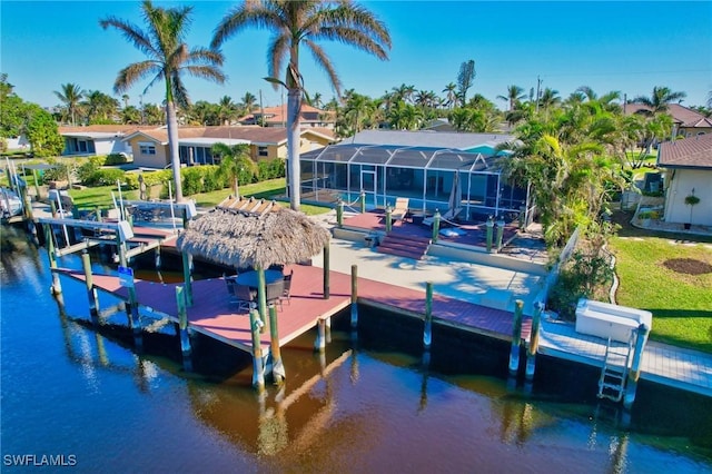 dock area with glass enclosure, a water view, and a yard