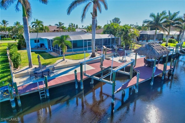 dock area with a water view, glass enclosure, and a lawn