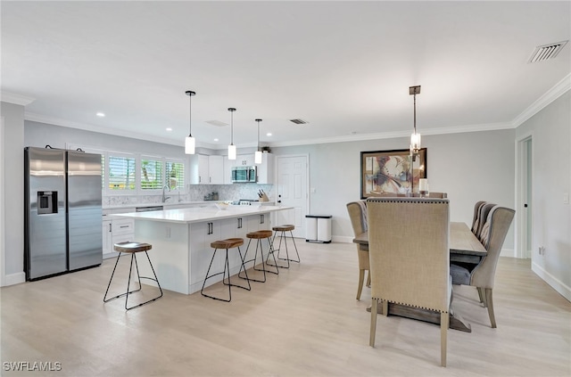 dining space with light wood-style flooring, recessed lighting, crown molding, and baseboards