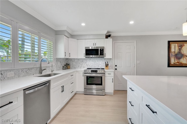 kitchen featuring tasteful backsplash, stainless steel appliances, sink, light hardwood / wood-style flooring, and white cabinetry