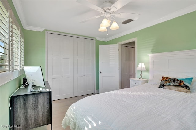 bedroom featuring light wood-type flooring, a closet, ornamental molding, and ceiling fan