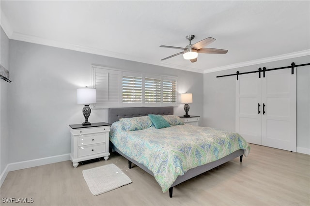 bedroom featuring light wood-type flooring, a barn door, baseboards, ornamental molding, and a ceiling fan