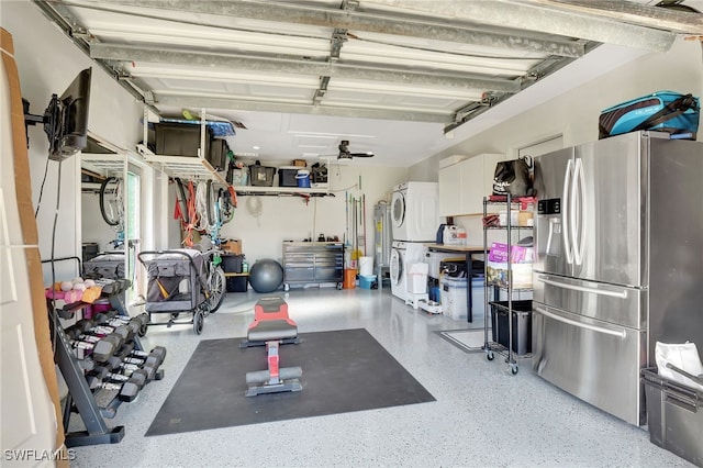 garage with stainless steel refrigerator with ice dispenser and stacked washer and clothes dryer