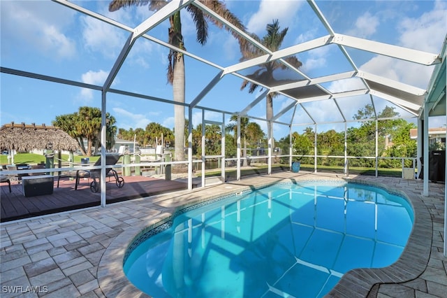 view of swimming pool featuring glass enclosure, a patio area, and a deck