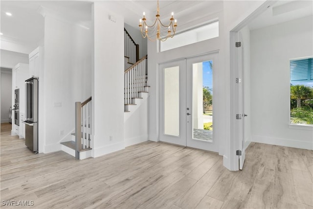 foyer featuring french doors, a healthy amount of sunlight, a chandelier, and light hardwood / wood-style flooring