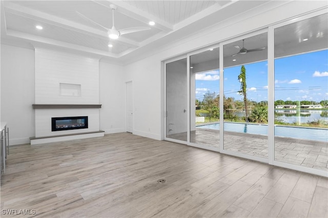 unfurnished living room featuring beamed ceiling, a fireplace, ceiling fan, and light hardwood / wood-style floors