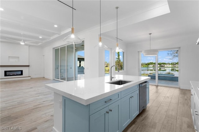 kitchen featuring sink, beam ceiling, a water view, an island with sink, and decorative light fixtures