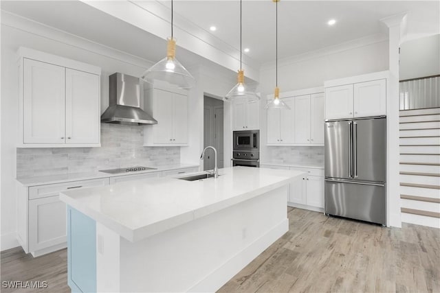 kitchen featuring pendant lighting, sink, white cabinetry, stainless steel appliances, and wall chimney exhaust hood