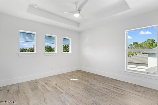 spare room featuring ceiling fan, a tray ceiling, and light hardwood / wood-style floors