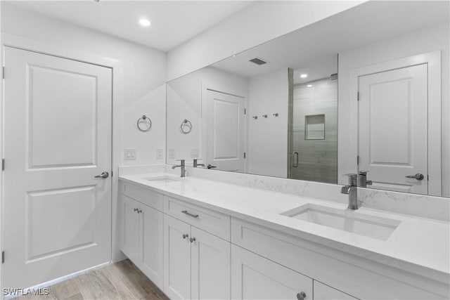 bathroom with vanity, hardwood / wood-style flooring, and a shower with door