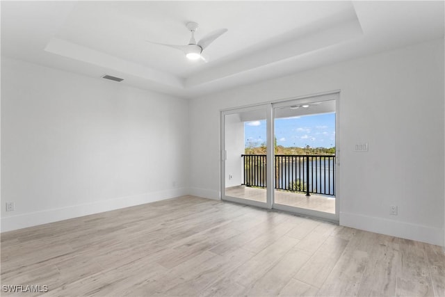 spare room featuring ceiling fan, a raised ceiling, and light hardwood / wood-style floors