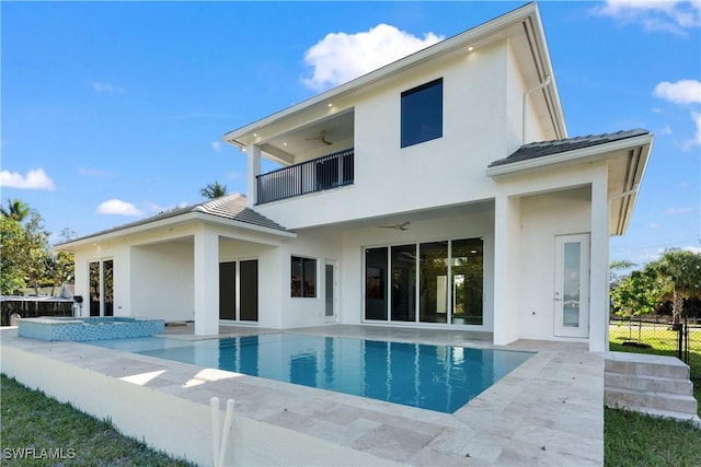 back of property featuring a swimming pool with hot tub, a balcony, ceiling fan, and a patio area