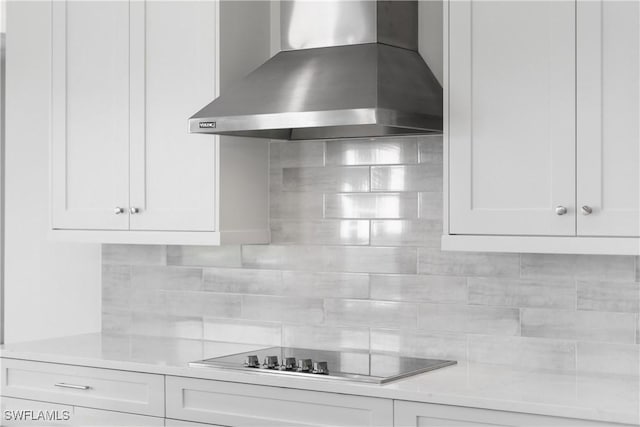 kitchen with white cabinetry, black electric stovetop, light stone counters, and wall chimney exhaust hood