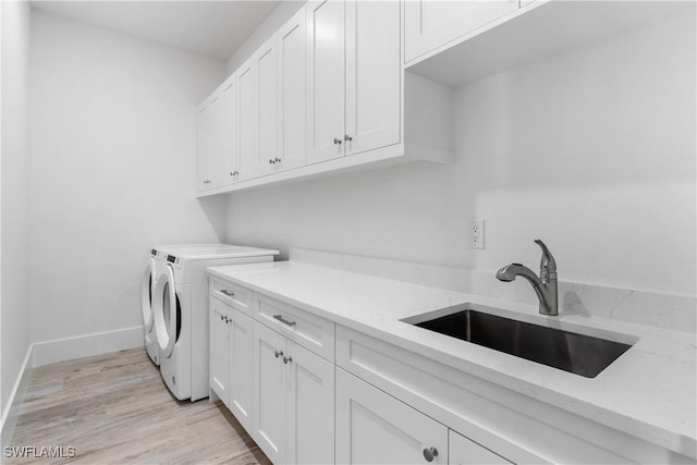 laundry area featuring cabinets, sink, washing machine and dryer, and light wood-type flooring