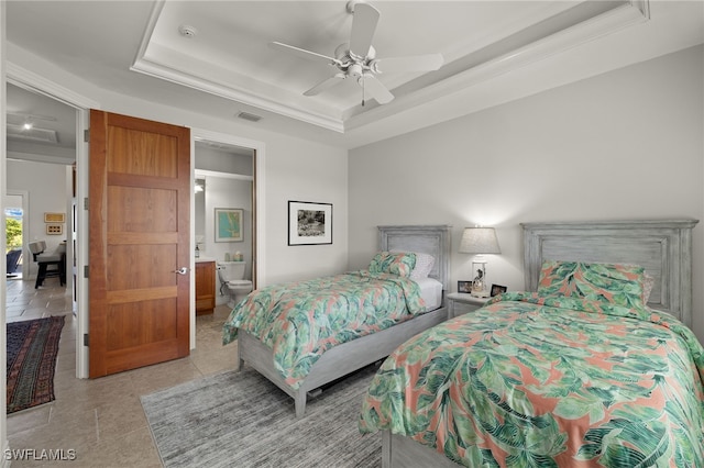 bedroom with ceiling fan, a raised ceiling, and ensuite bathroom