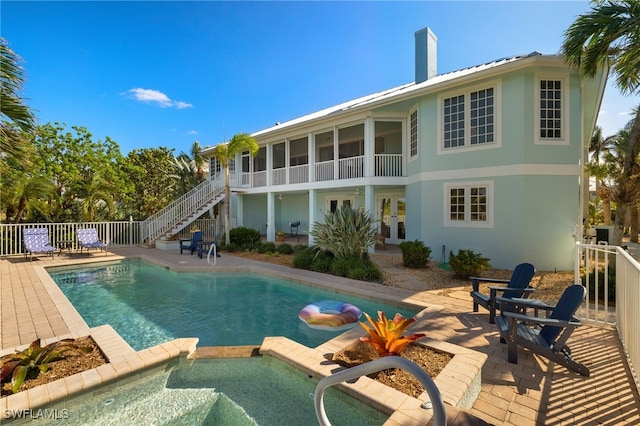 view of pool with a sunroom, an in ground hot tub, and a patio