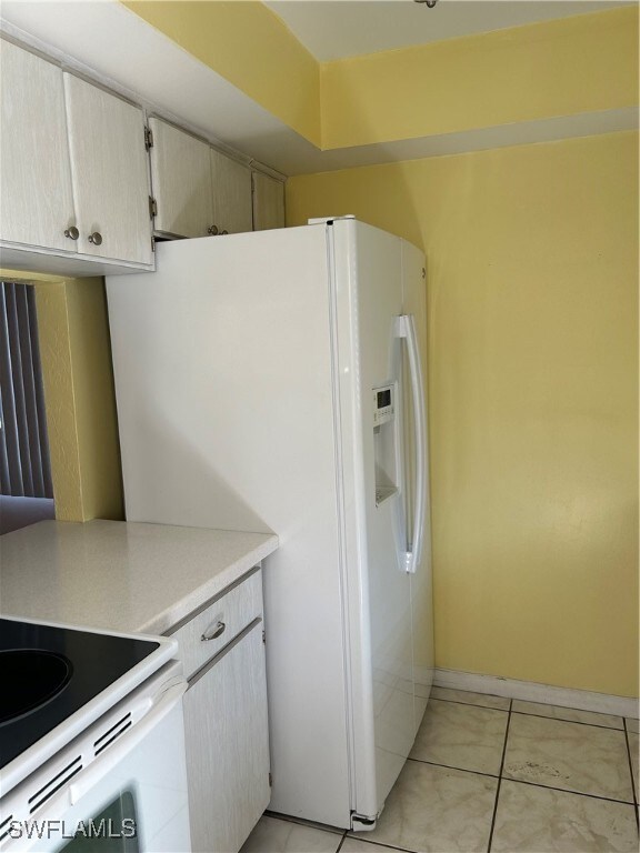 kitchen with light tile patterned floors and white refrigerator with ice dispenser