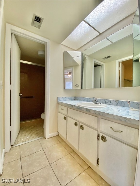 bathroom featuring tile patterned floors, vanity, toilet, and a skylight