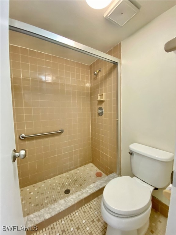 bathroom with tiled shower, tile patterned flooring, and toilet