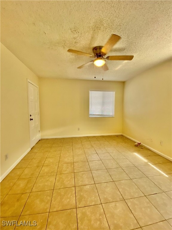 empty room with ceiling fan, light tile patterned flooring, and a textured ceiling